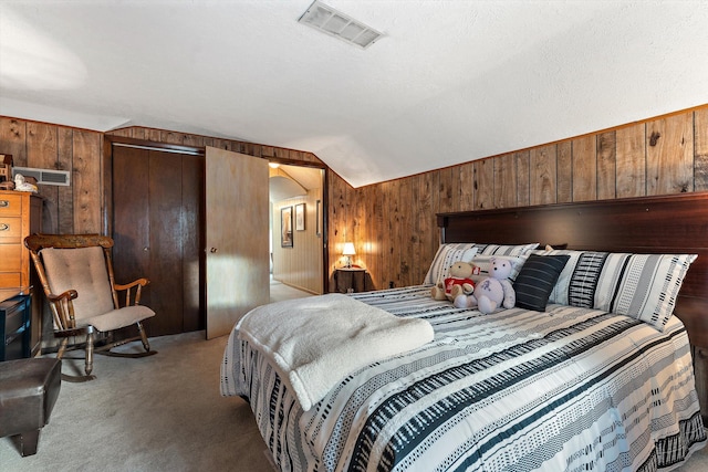 carpeted bedroom featuring a textured ceiling, vaulted ceiling, and wooden walls