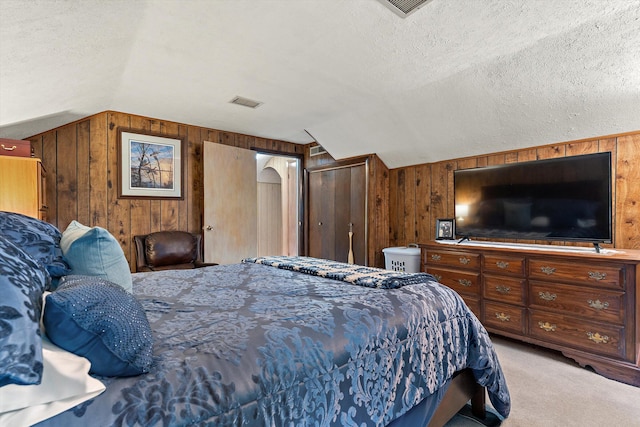 carpeted bedroom featuring lofted ceiling, a textured ceiling, and wooden walls