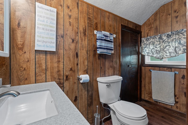 bathroom with wood walls, wood-type flooring, a textured ceiling, vaulted ceiling, and toilet