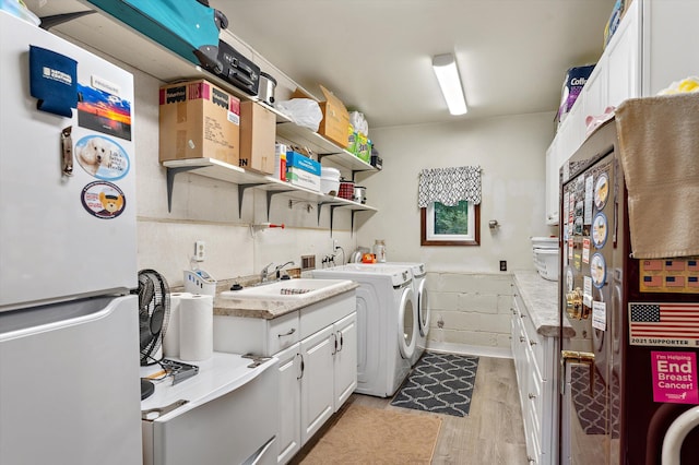 washroom with cabinets, light hardwood / wood-style flooring, washer and clothes dryer, and sink