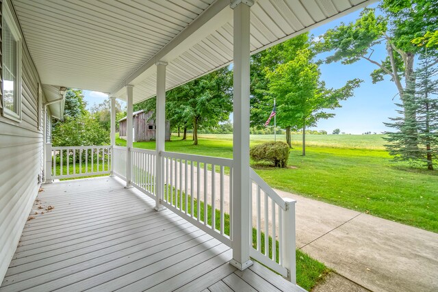 wooden terrace featuring a porch and a yard