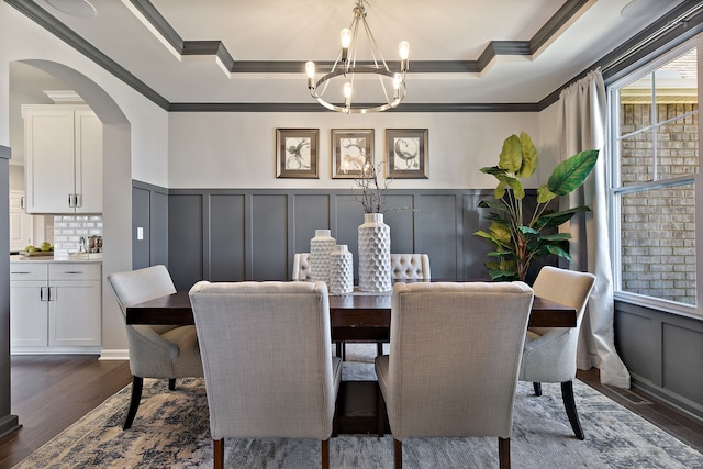 dining space with dark hardwood / wood-style floors, ornamental molding, a tray ceiling, and an inviting chandelier