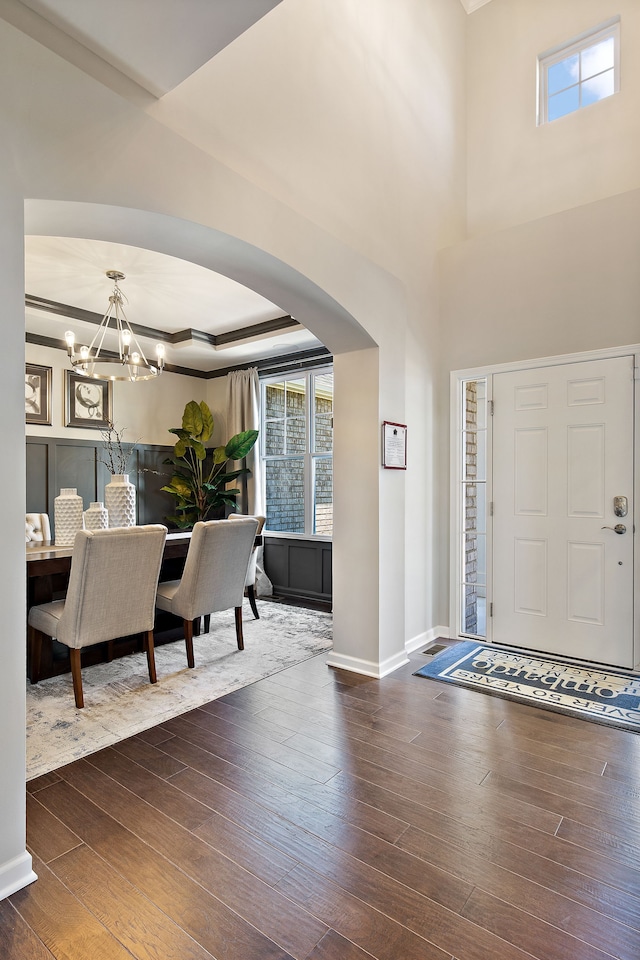 foyer entrance with dark hardwood / wood-style floors, a raised ceiling, and a notable chandelier