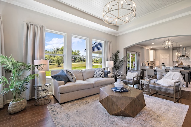 living room featuring hardwood / wood-style floors, ornamental molding, and a notable chandelier