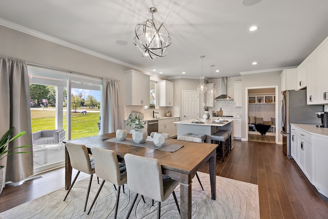 dining area with sink, crown molding, dark wood-type flooring, and a notable chandelier