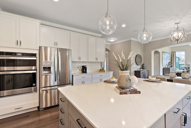 kitchen with appliances with stainless steel finishes, ornamental molding, dark wood-type flooring, pendant lighting, and white cabinets