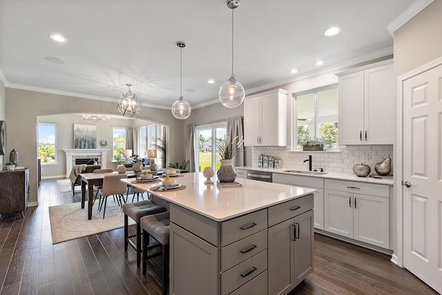 kitchen featuring sink, white cabinetry, dark wood-type flooring, and hanging light fixtures