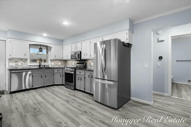 kitchen featuring appliances with stainless steel finishes, backsplash, dark countertops, and a sink