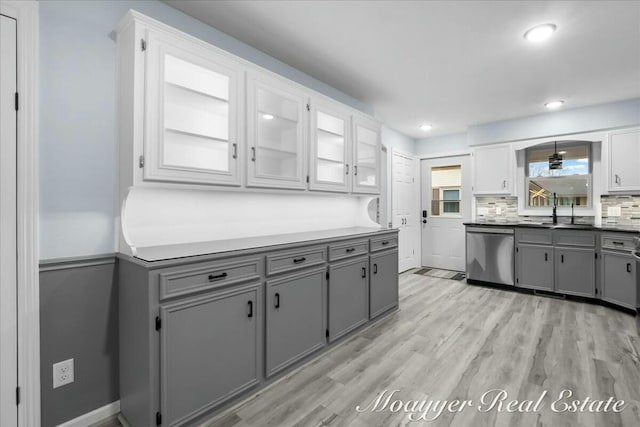 kitchen with a sink, tasteful backsplash, gray cabinets, and dishwasher