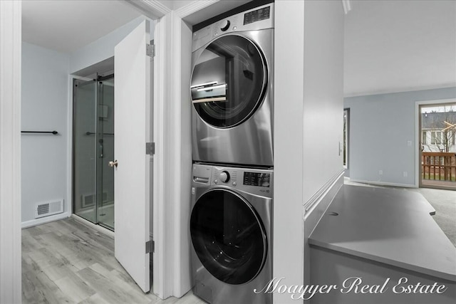 laundry room with laundry area, wood finished floors, visible vents, and stacked washer / drying machine