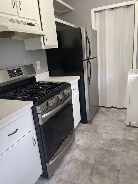 kitchen with washer / dryer, white cabinetry, and stainless steel gas range oven