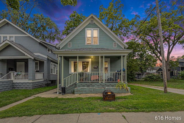 bungalow-style house featuring a lawn, a porch, and a fire pit