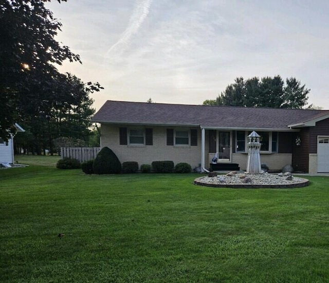 single story home with a garage and a yard