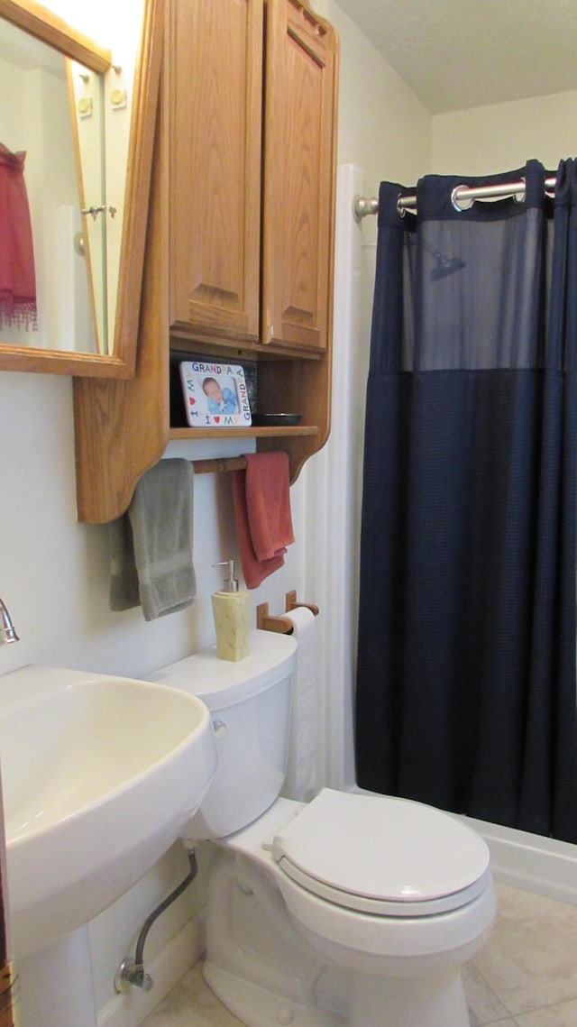 bathroom featuring a shower with shower curtain, toilet, and sink