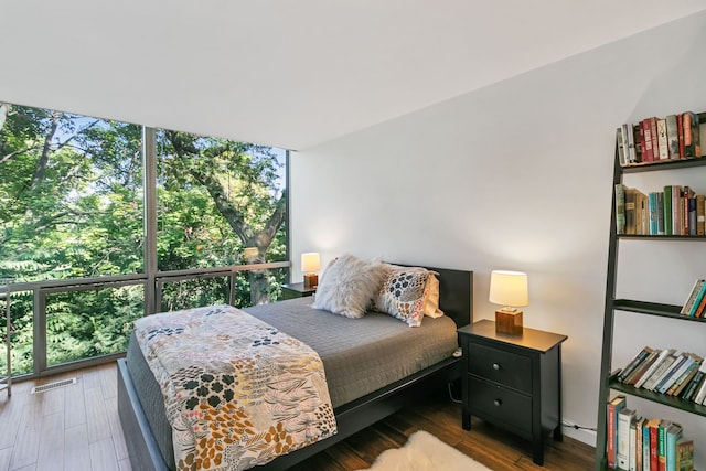 bedroom featuring dark hardwood / wood-style flooring and a wall of windows