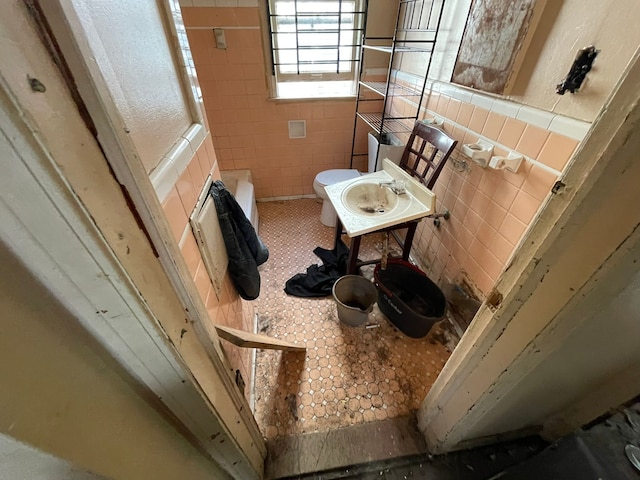 bathroom featuring toilet, tile walls, and sink