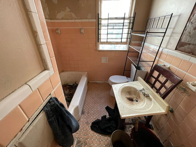 bathroom with sink, a bathtub, toilet, and tile walls