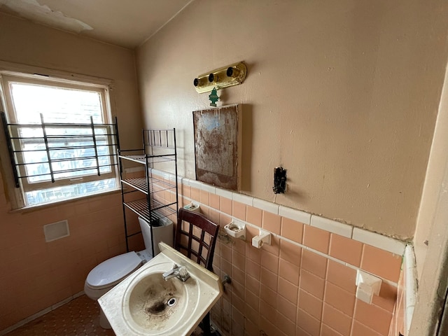 bathroom featuring sink, tile walls, and toilet