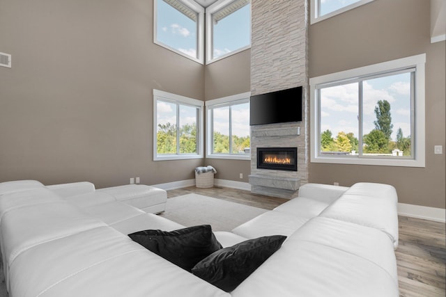 living room with a fireplace, a high ceiling, and light hardwood / wood-style flooring