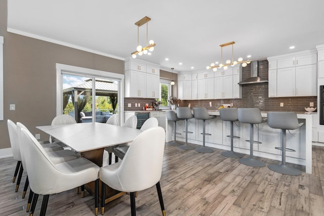 dining room with light hardwood / wood-style floors, an inviting chandelier, and ornamental molding