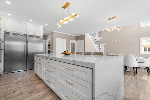 kitchen with white cabinets, pendant lighting, a kitchen island, and built in fridge