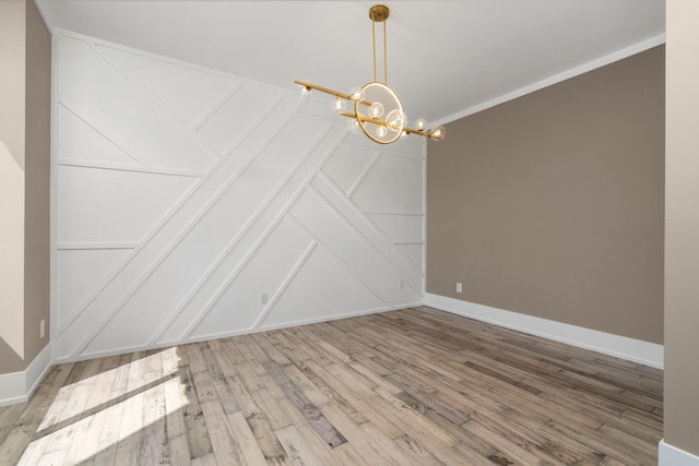 unfurnished dining area featuring wood-type flooring, ornamental molding, and a chandelier