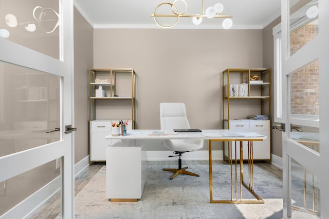 office space featuring ornamental molding, a notable chandelier, and light wood-type flooring