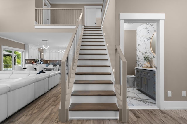 staircase featuring crown molding, a chandelier, and hardwood / wood-style flooring