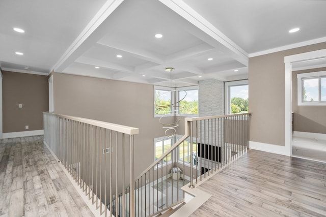 corridor with beamed ceiling, a healthy amount of sunlight, coffered ceiling, and light hardwood / wood-style flooring