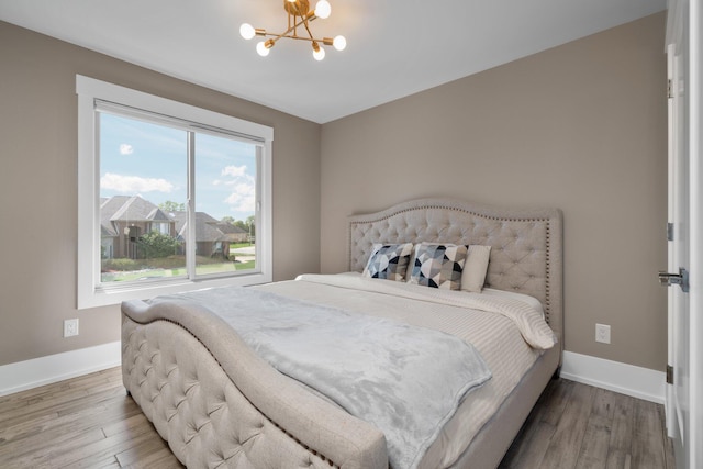 bedroom with hardwood / wood-style floors and a notable chandelier