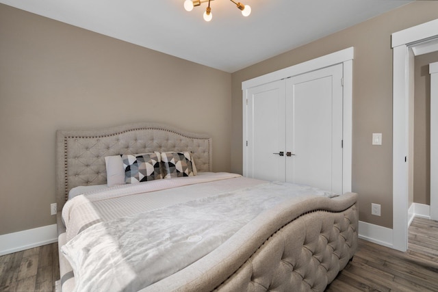 bedroom featuring dark hardwood / wood-style floors, an inviting chandelier, and a closet