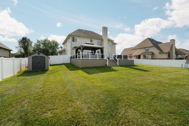 rear view of property featuring a lawn, a wooden deck, and a storage shed