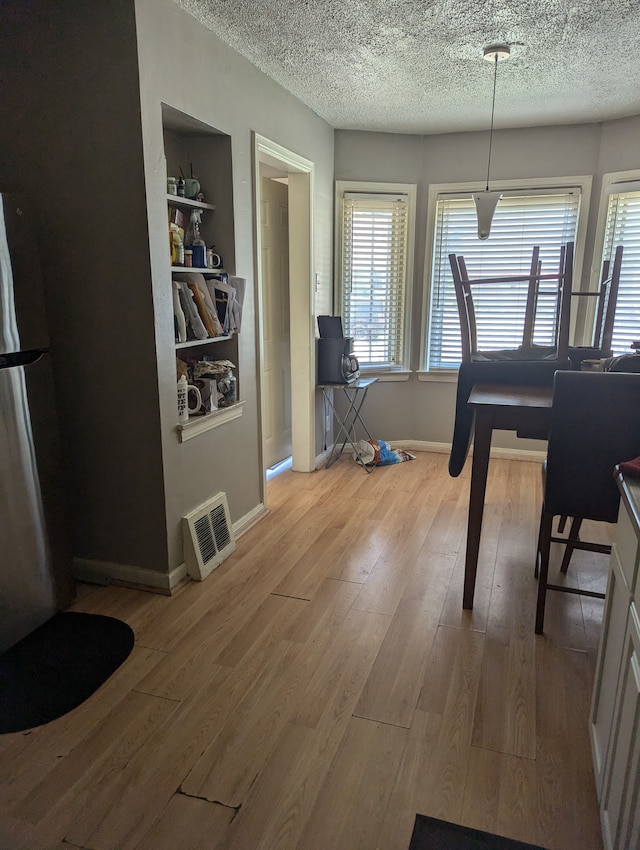 dining room with light hardwood / wood-style floors and a textured ceiling