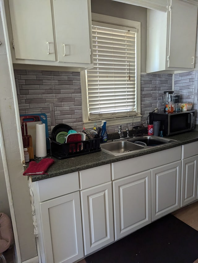 kitchen with white cabinets, decorative backsplash, and sink