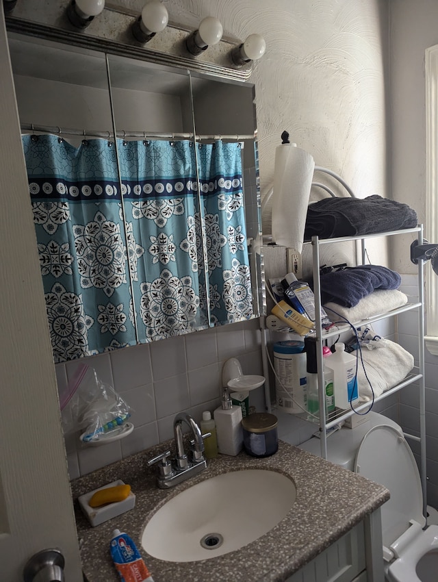 bathroom with curtained shower, vanity, tile walls, and toilet