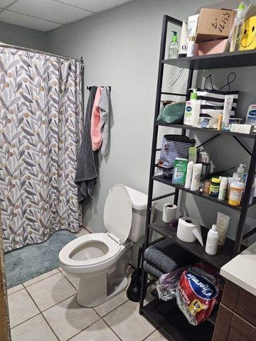 bathroom featuring a paneled ceiling, a shower with curtain, toilet, and tile patterned floors