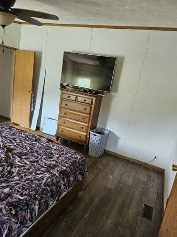 bedroom with ceiling fan, dark hardwood / wood-style flooring, crown molding, and a textured ceiling