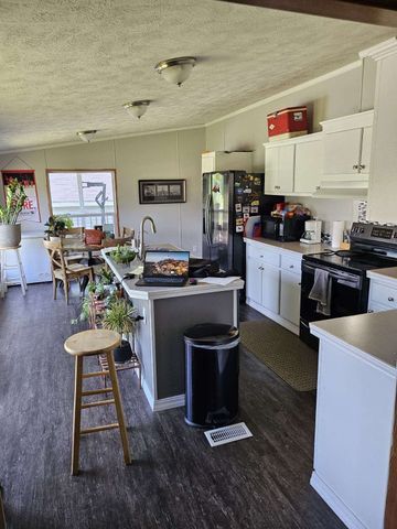 kitchen with dark hardwood / wood-style flooring, a center island with sink, white cabinets, and stainless steel appliances