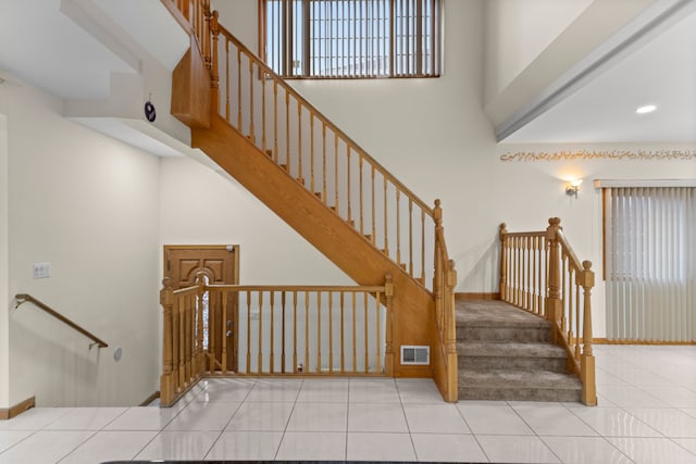 stairway featuring tile patterned flooring and a towering ceiling