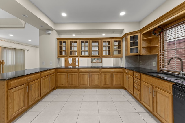 kitchen featuring kitchen peninsula, dark stone counters, sink, light tile patterned floors, and black dishwasher