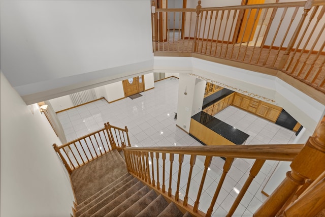 stairway featuring tile patterned flooring and a high ceiling