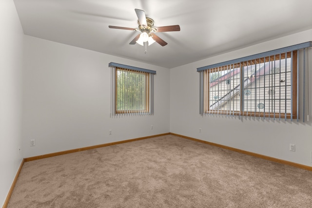 carpeted spare room featuring a wealth of natural light and ceiling fan