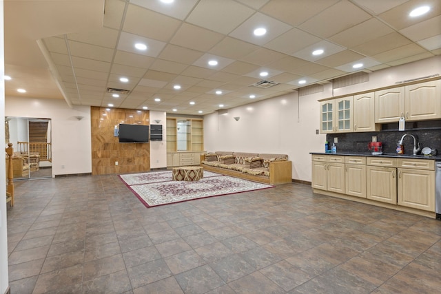 interior space with backsplash, a paneled ceiling, sink, and stainless steel dishwasher