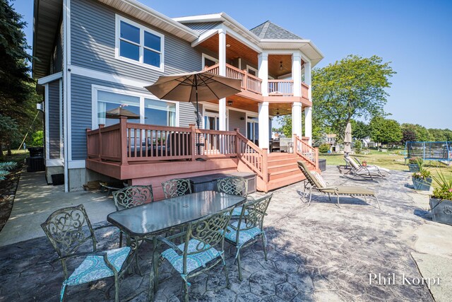 250 Shore Dr, Wayland, MI 49348 - rear view of house featuring a balcony, a patio area, outdoor dining space, a trampoline, and a wooden deck