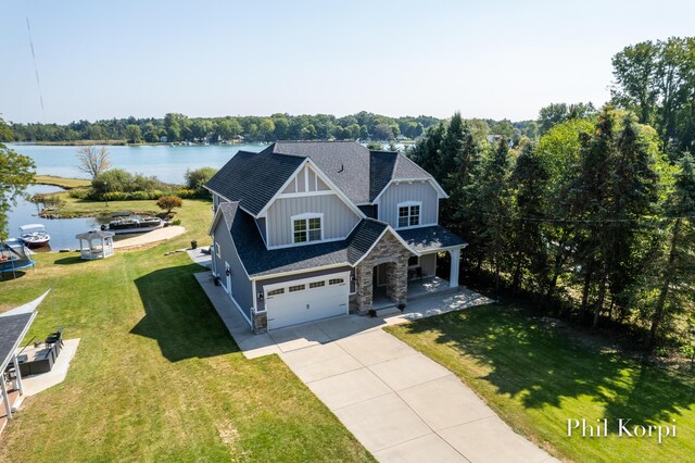 250 Shore Dr, Wayland, MI 49348 - craftsman-style home with driveway, an attached garage, stone siding, covered porch, and a water view