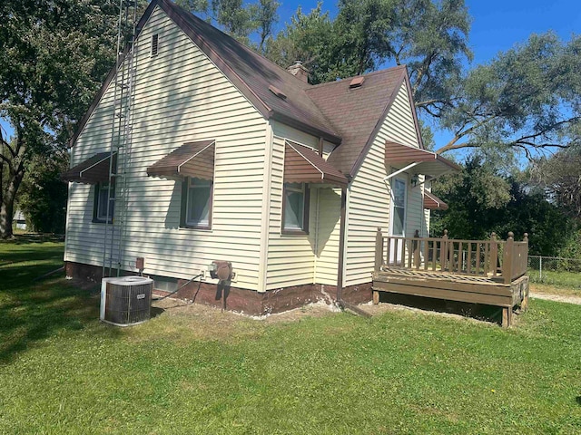 view of side of property with a yard, a wooden deck, and central AC