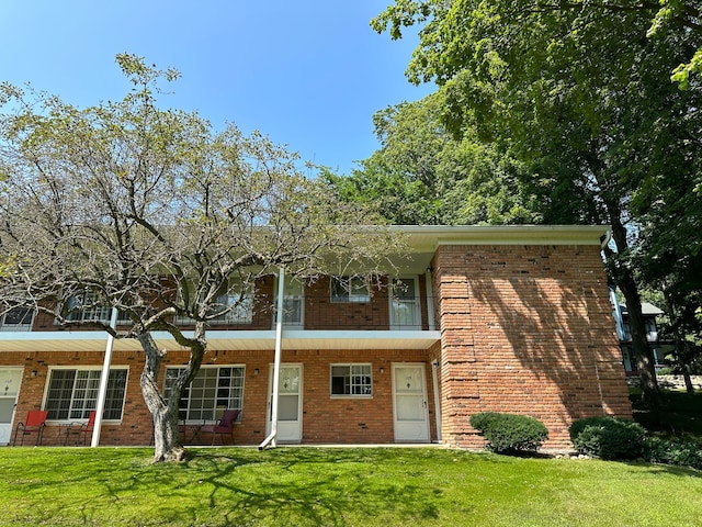 view of front of home featuring a front lawn, a balcony, and brick siding