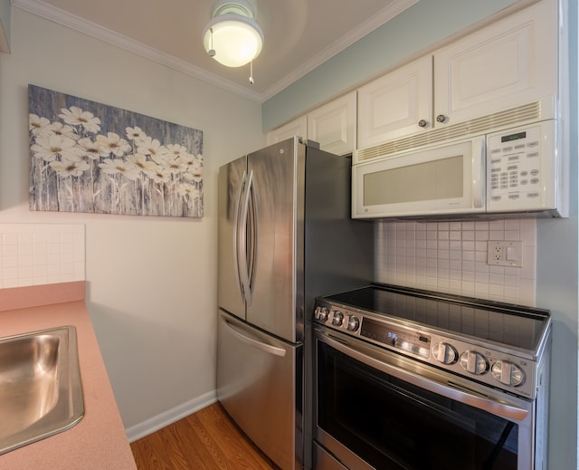 kitchen featuring sink, stainless steel appliances, backsplash, light wood-type flooring, and ornamental molding