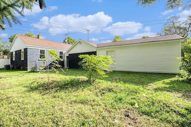 rear view of house featuring a lawn and cooling unit