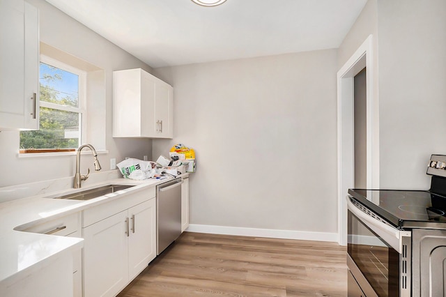 5344 Lapeer Rd, Burton, MI 48509 - kitchen featuring appliances with stainless steel finishes, a sink, light wood finished floors, white cabinetry, and baseboards